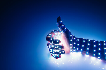 thumbs up hand covered with blue led lights, illuminated background