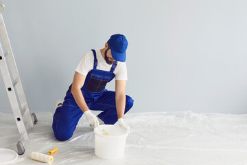 Bearded worker painter taking paint from bucket