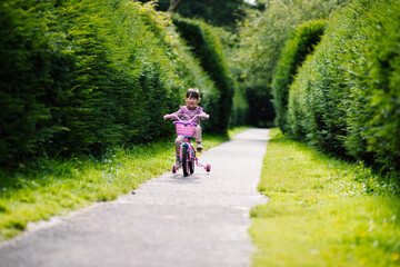 young girl ridding bicycle in the  summer garden morning