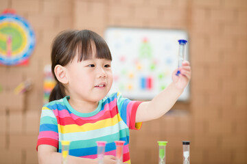 young girl plying hourglass learning the time for homeschooling