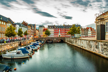 Fototapeta premium Early morning shot of a city canal with small boats and colorful houses in Copenhagen, Denmark, nybrogade, Holmanskanal