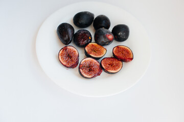 Ripe and sweet figs cut and arranged in a plate on a white background with free space. Fruits and vegetarianism