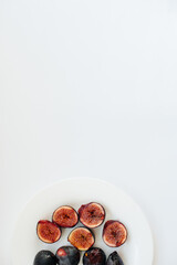 Ripe and sweet figs cut and arranged in a plate on a white background with free space. Fruits and vegetarianism