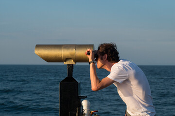 young male traveler with  spyglass on the sea beach