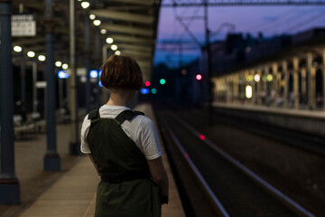 young woman traveler wait train on the station in the night