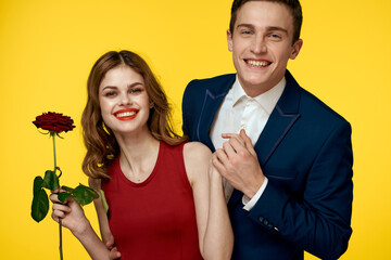 lovers man and woman with a red rose in their hands hugging on a yellow background romance relationship love family
