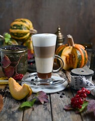 Pumpkin spice latte with whipped cream and cinnamon in glass on rustic wooden background. Selective focus.