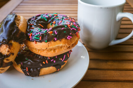 Sweet Donuts piled up beside a cup of coffee on a closeup image