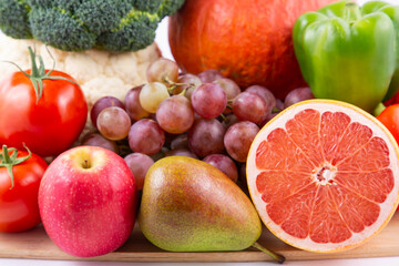 Group vegetables and Fruits Apples, grapes, oranges, and bananas in the wooden basket with carrots, tomatoes, guava, chili, eggplant, and salad on the table.