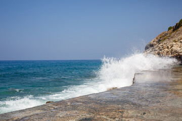 Sea water beats against rocky rocks and makes waves with foam