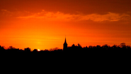 Church steeple and tree silhouette at sunset
