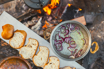 Flat lay view of camp fire cooking, breads are in a row, a tea pot and onion pan is on the fire