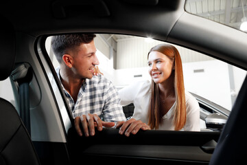 Young couple choosing their new car in a car shop