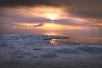Frozen beach and sun at horizon