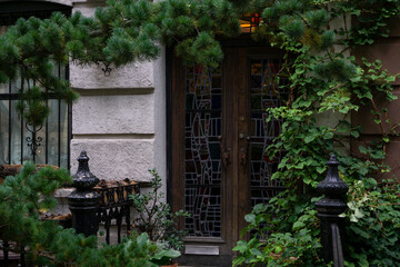 Fototapeta na wymiar Vintage style of an exterior entrance to an apartment building surrounded by plants and trees