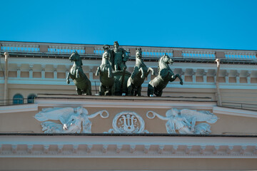 Ostrovsky Square, Saint Petersburg, Russia, 11.10.2020. Ancient green sculpture of cavalry, horses on facade of yellow building of Russian State Drama Theater named A.S. Pushkin. White angels relief
