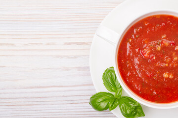 Gazpacho in a white plate and basil