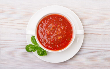 Gazpacho in a white plate and basil
