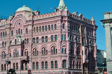 Fototapeta na wymiar Ostrovsky Square, Saint Petersburg, Russia, 11.10.2020. Pink red historical building Bazin's House in neorussian style. Decorative facade with turrets, windows, stucco. Blue sky backdrop