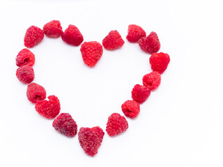 Red raspberries are laid out in the shape of a heart on a white background. Love for raspberries