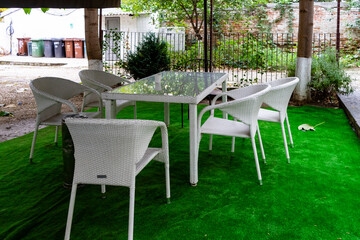 Patio garden terrace table and six chairs on an artificial green grass carpet. - 384645537