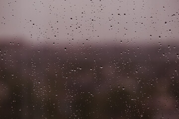 A blurred background of nature through glass with drops
