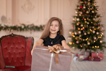 A little girl opens a Christmas present from Santa. Christmas tale. Happy childhood