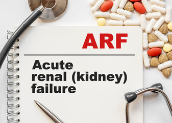 Page in notebook with ARF Acute renal kidney failure on white background with stethoscope and group...