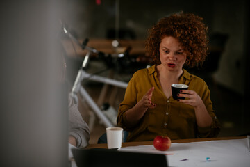Businesswomen drinking coffee in office.. Colleagues discussing work in office.