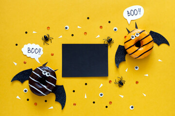 Happy halloween holiday concept. Funny food for kids - scared donuts on bright yellow background as...