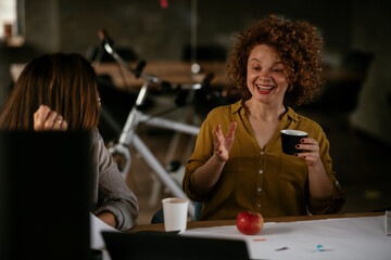 Businesswomen drinking coffee in office.. Colleagues discussing work in office.