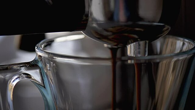 Espresso coffee pouring and dripping into espresso cup in slow motion extreme close up
