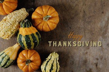 Rustic Happy Thanksgiving graphic with top view of pumpkins and gourds on old wood background for...