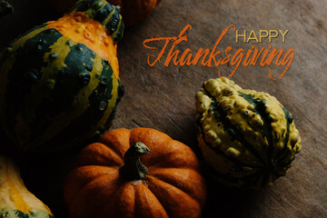 Autumn background with happy Thanksgiving text beside pumpkin and gourds for holiday.