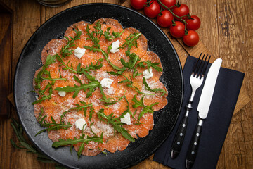 Salmon carpaccio with cheese and arugula
