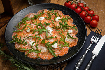 Salmon carpaccio with cheese and arugula
