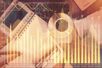 Double exposure of financial graph hologram over desktop with phone. Top view. Mobile trade...