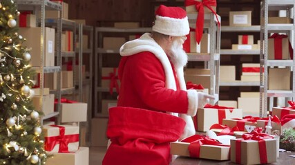 Old funny Santa Claus, Saint Nicholas packing presents gift boxes in sack bag preparing post shipping fast xmas delivery parcels walking in workshop. Merry Christmas shipping delivery concept. - Powered by Adobe