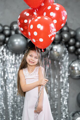 Little girl with red balloons celebrates her birthday