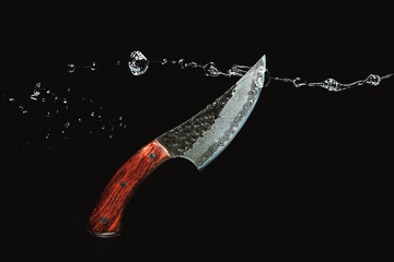 Damascus steel knife cuts water on a black background. High quality photo