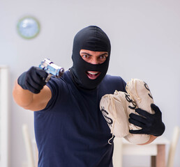 Robber wearing balaclava stealing valuable things