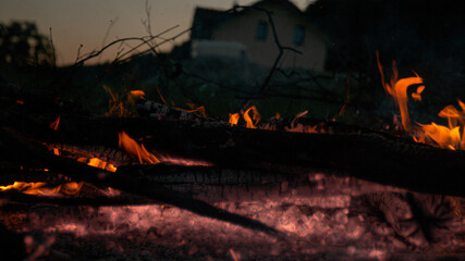 CLOSE UP: Embers still glow and gently burn in the backyard of someone's house.