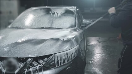 Man washes his car at self-service car wash, covers car with washing foam. - Powered by Adobe