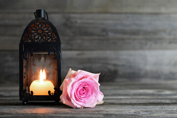 Memorial candle and pink rose on wooden background