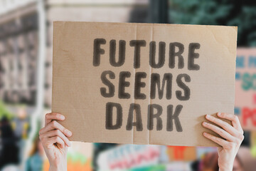 The phrase " Future seems dark " on a banner in men's hand with blurred background. Futurism. Apocalypse. Collapse. Bad. Cataclysm. Negative. Pessimistic