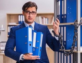 Young man standing next to the shelf with folders