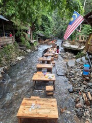 A restaurant in a stream in Malaysia, people preparing a table in a stream, a restaurant in the forest.