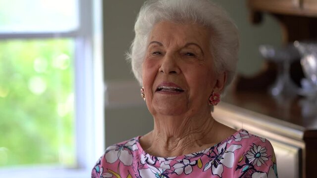 Smiling portrait older woman looking talking to camera conference calling at home. Smiling senior mature adult grandmother speak to webcam do video chat communicate online sit on sofa, web cam view