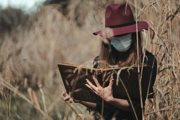 Young enchantress casting a spell in the forest, wearing a mask