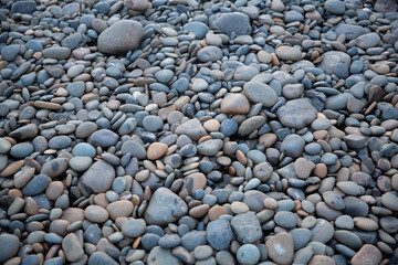 Rocky texture round grey and tan river rocks in a creek bed all gathered together